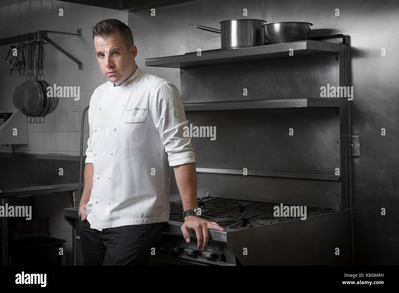 Portrait of pastry chef leaning against hob in kitchen Stock Photo