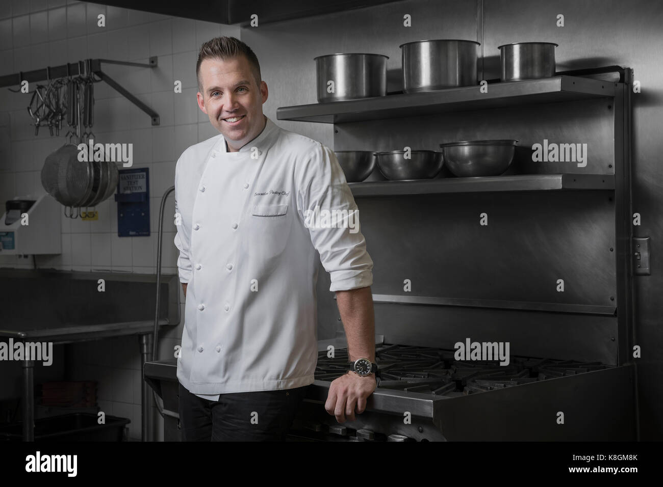 Portrait of happy pastry chef leaning against hob in kitchen Stock Photo