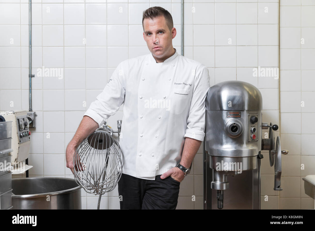 Portrait of pastry chef holding industrial whisk in kitchen Stock Photo