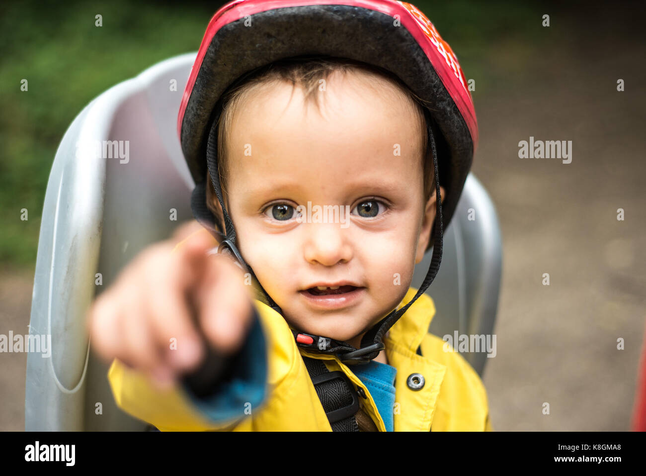 Portrait of young boy sitting in child's seat of adult bicycle, pointing Stock Photo