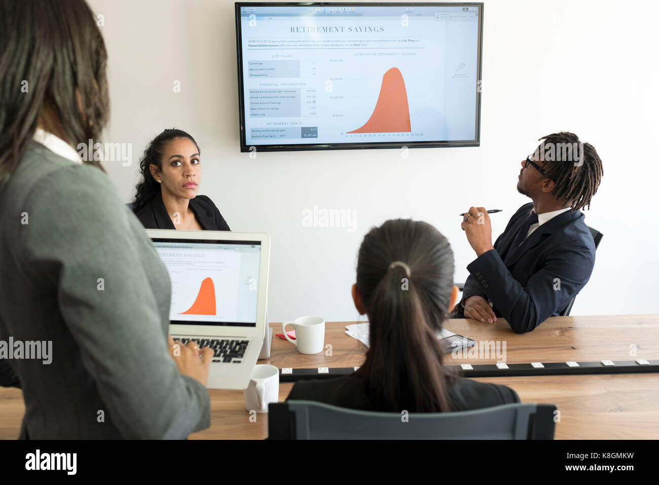 Businessman and businesswomen, in office, looking at data graphs Stock Photo