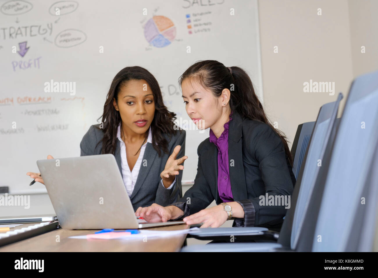 Two businesswomen in office, looking at laptop screen Stock Photo