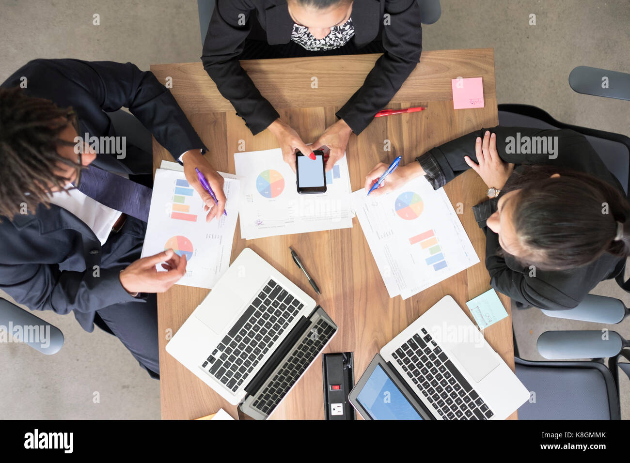 Businessman and businesswomen, in office meeting, using laptops, looking at data, overhead view Stock Photo
