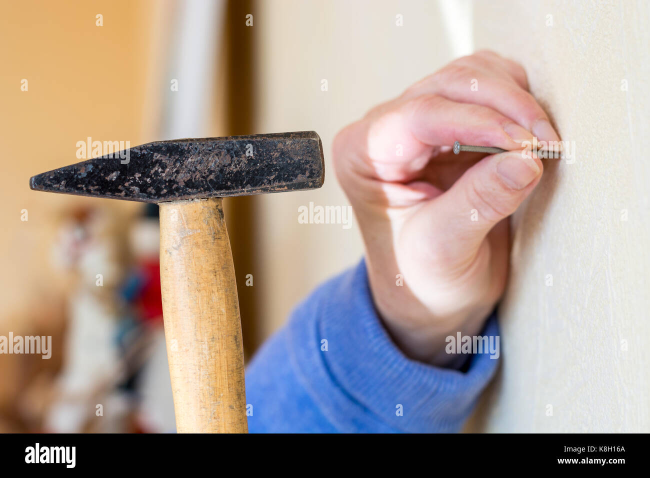 Hammer a nail into a wall as a close up from the side Stock Photo - Alamy