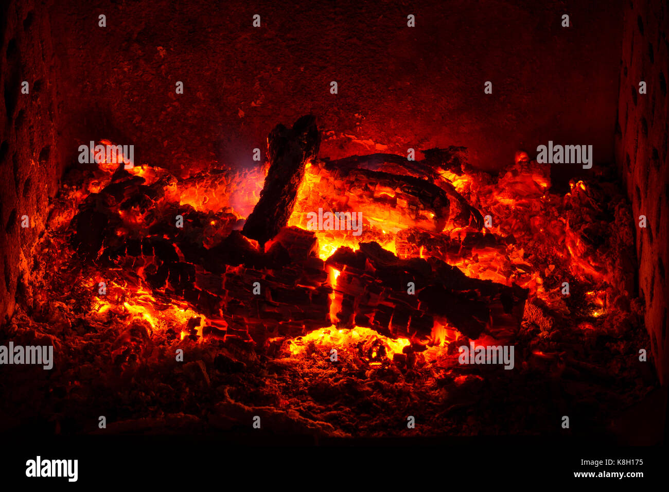 Embers with burned logs and ashes in a fireplace with warm atmosphere Stock Photo