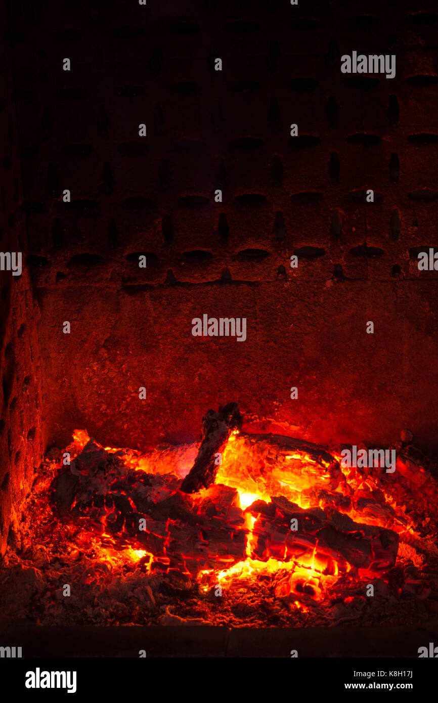 Embers with burned logs and ashes in a fireplace with warm atmosphere Stock Photo
