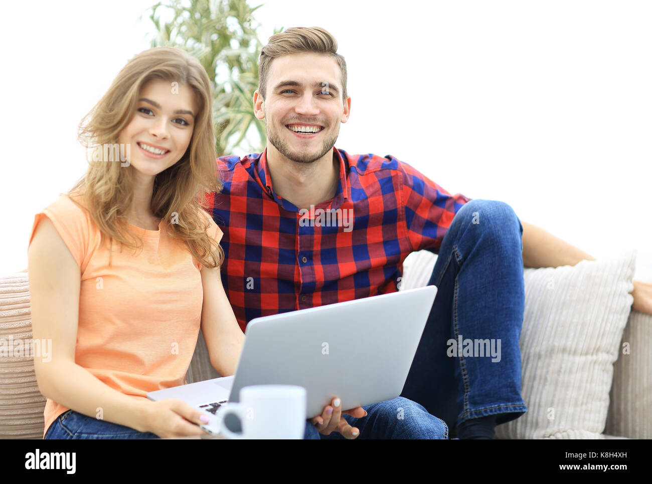 young couple of students uses a laptop sitting on sofa Stock Photo - Alamy