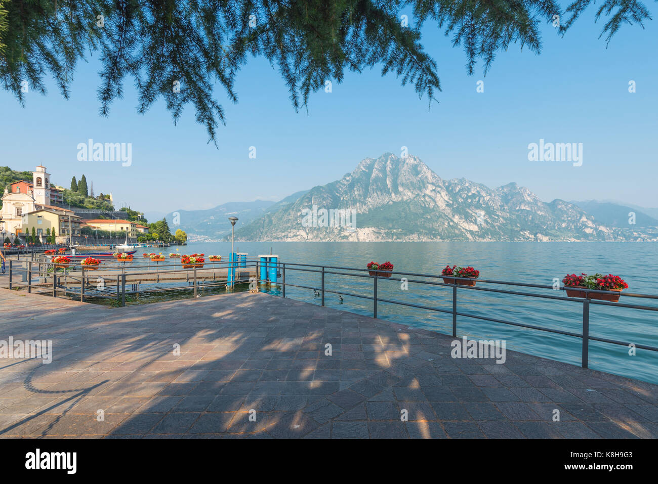 View from the lakeside at central square in medieval Riva di Solto on mountains in the evening sun at Lake Iseo, Lombardy, Italy Stock Photo