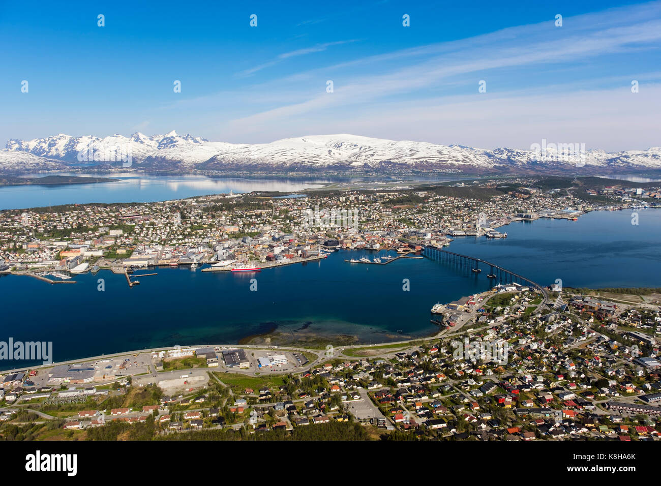 High view above city on Tromsoya island with snow-capped distant mountains seen from Mount Storsteinen. Tromso, Troms, Norway, Scandinavia Stock Photo