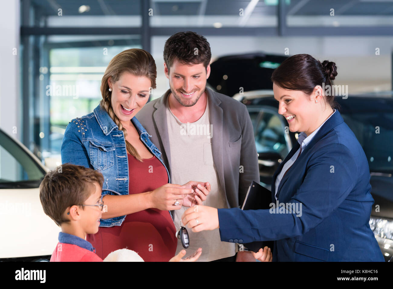 Car dealer giving key to new auto to family Stock Photo - Alamy