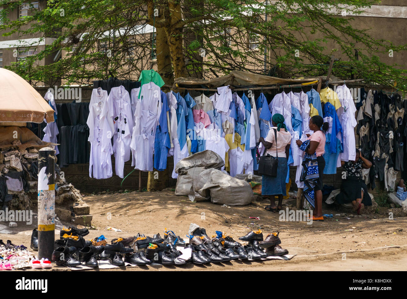 Women browse childrens school clothes on dispay by roadside, Nairobi, Kenya Stock Photo