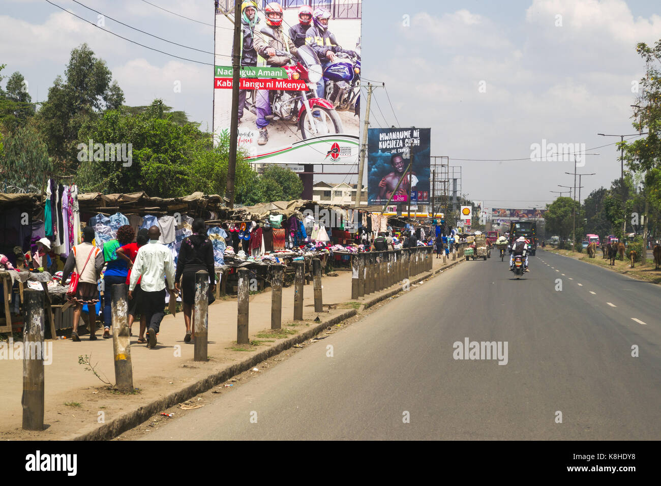 Clothes stalls line the pavement along Jogoo road as people and traffic go past, Nairobi, Kenya Stock Photo