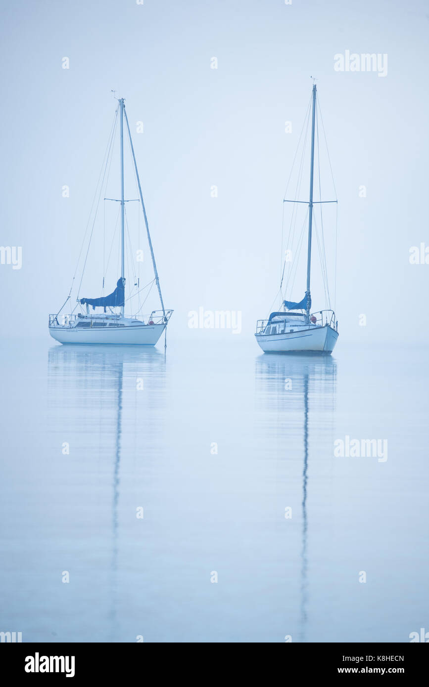 two sailboats on the water in the fog no horizon, abstract Stock Photo
