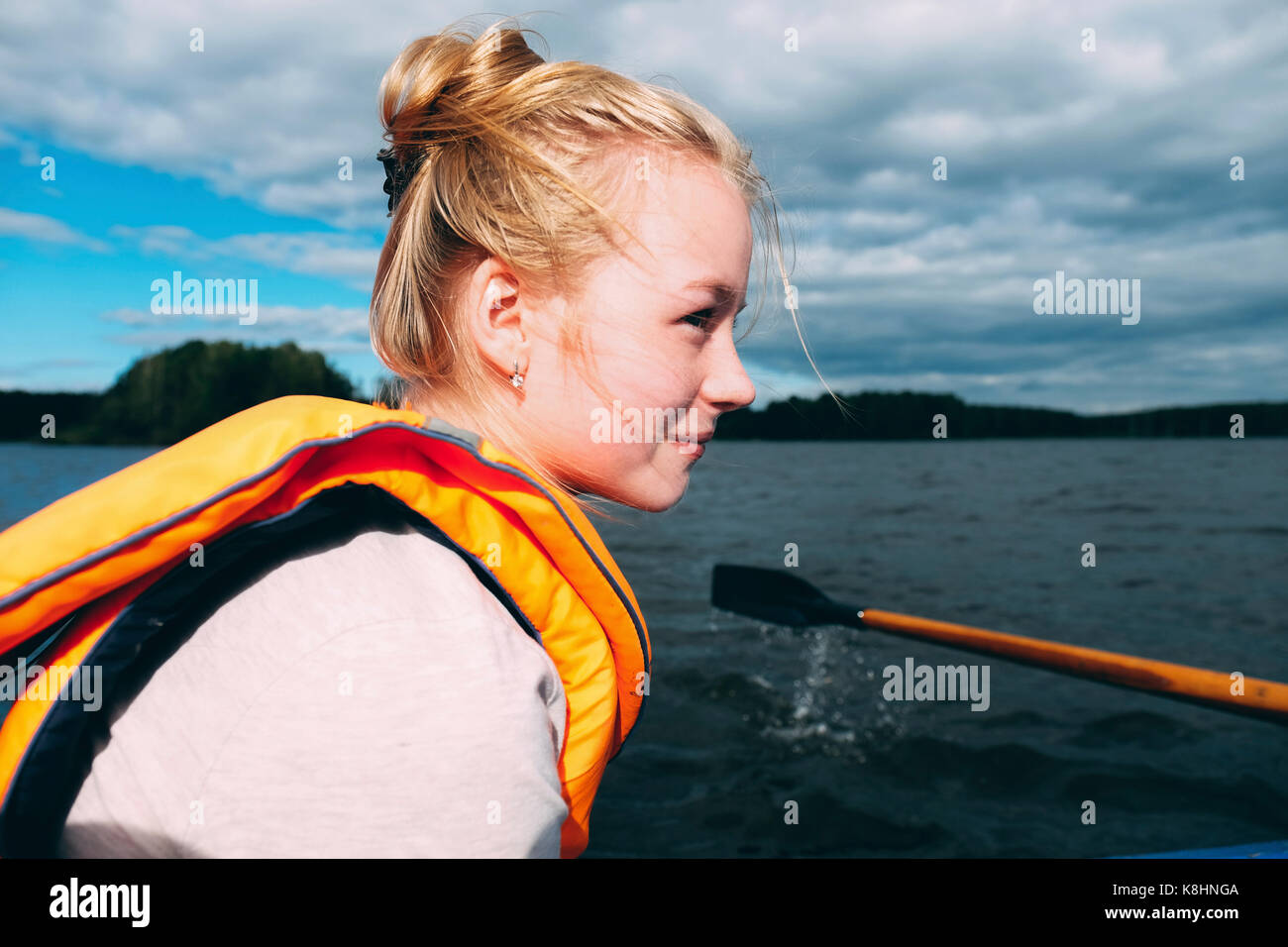 Side view of woman canoeing on sea against cloudy sky Stock Photo