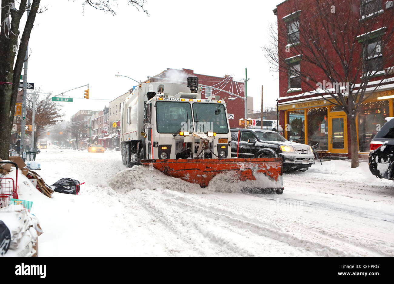 A garbage truck fitted with a snow plow clears snow during Winter Storm