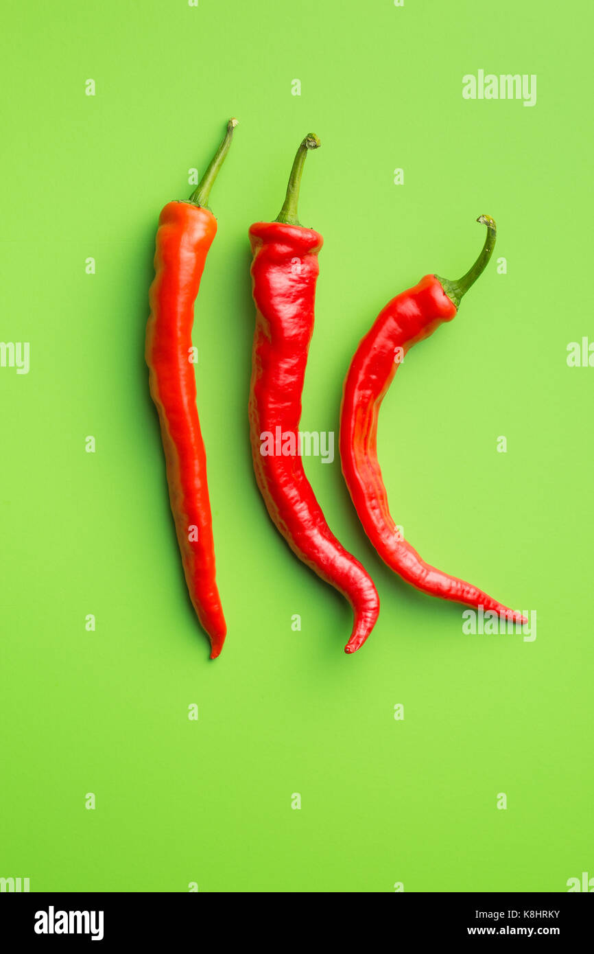 Red chili peppers on green background Stock Photo - Alamy