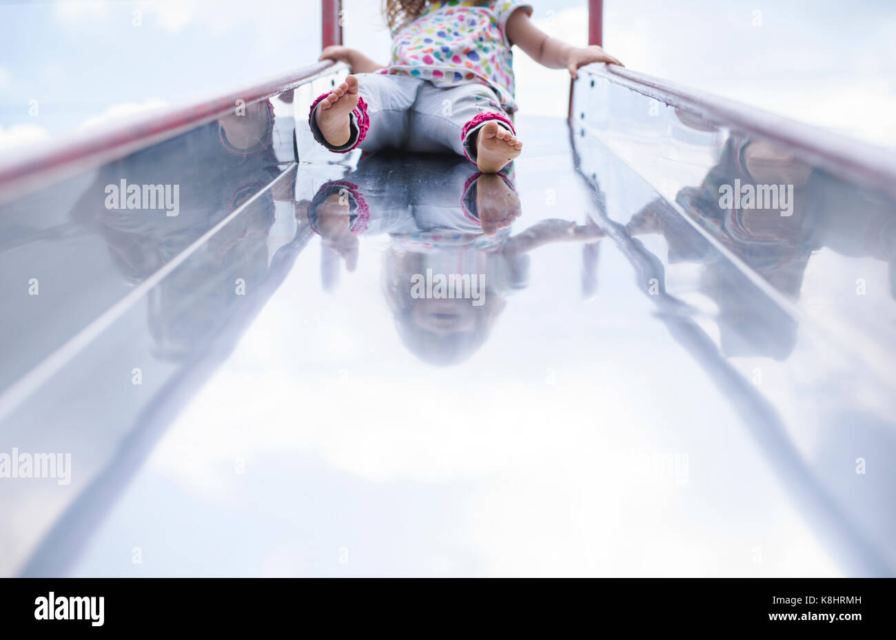 Low section of girl playing on slide at playground Stock Photo