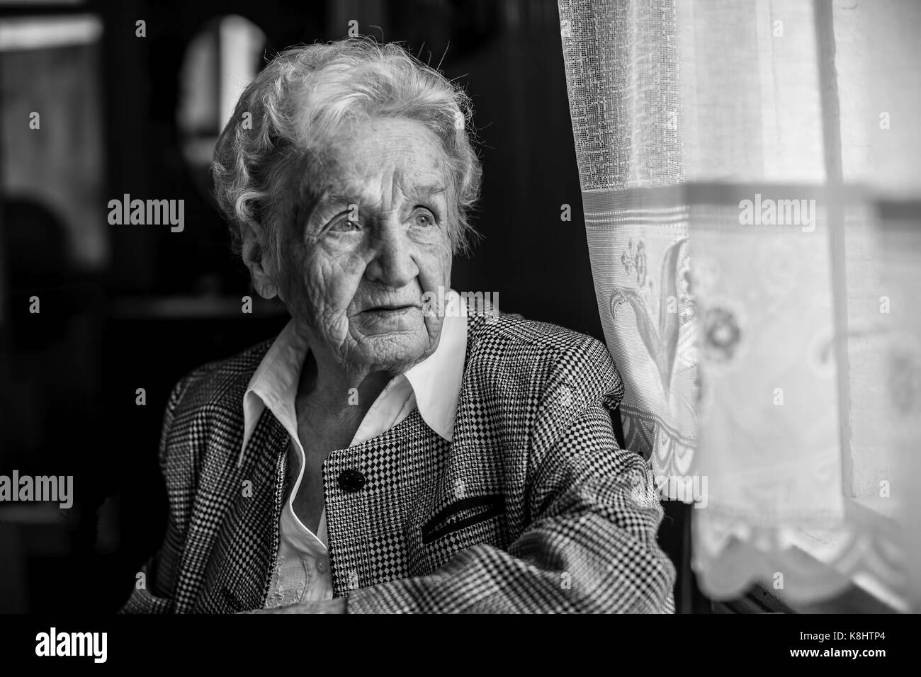Portrait of stern old women, black and white near the window. Stock Photo