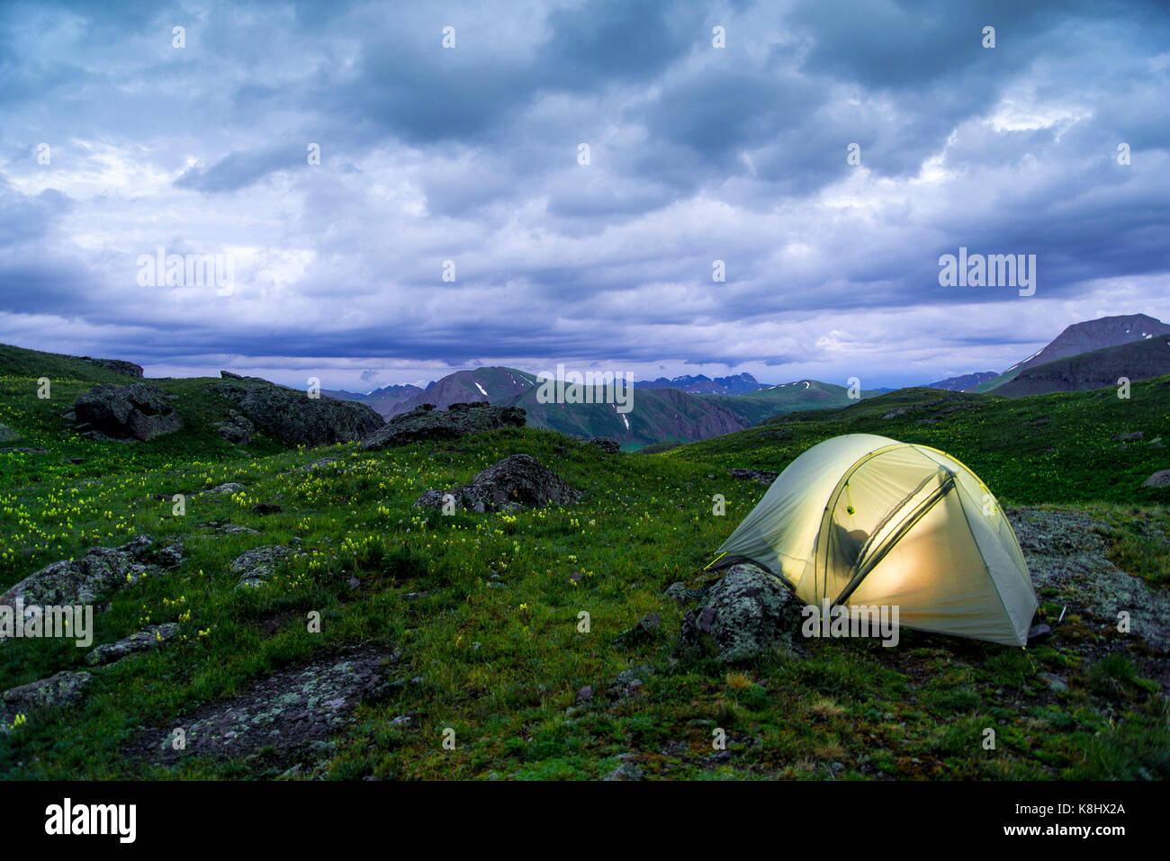 Illuminated tent on field against stormy clouds at San Juan National Forest Stock Photo