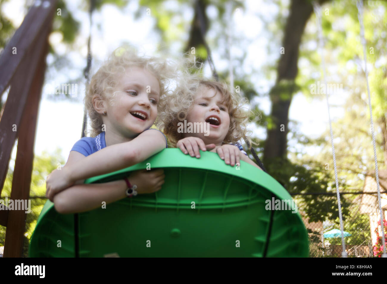 Low angle view of sisters playing on outdoor play equipment at playground Stock Photo