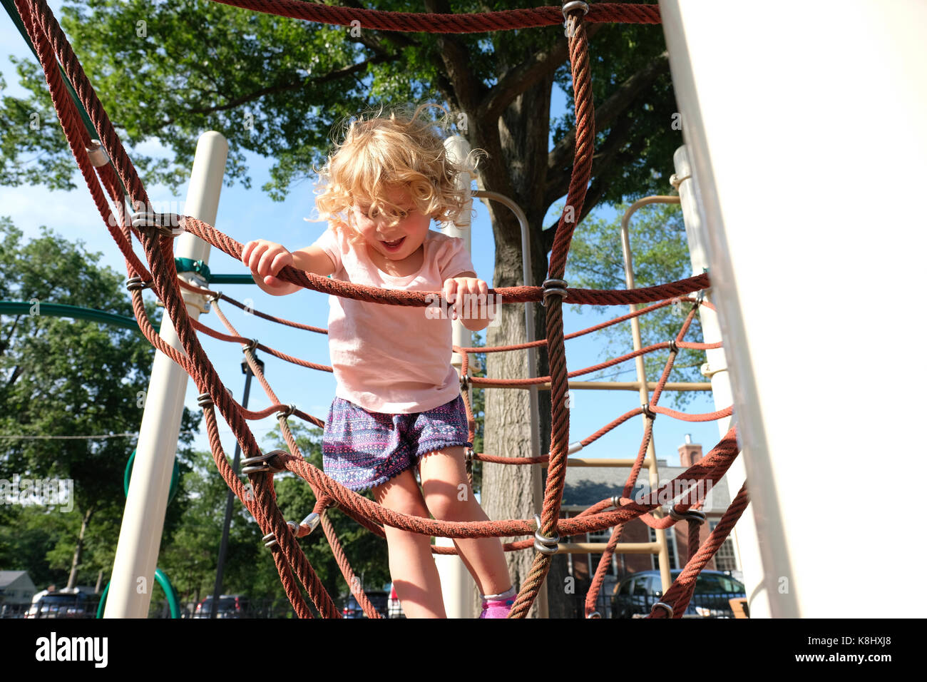 Carefree girl climbing rope on jungle gym at playground Stock Photo