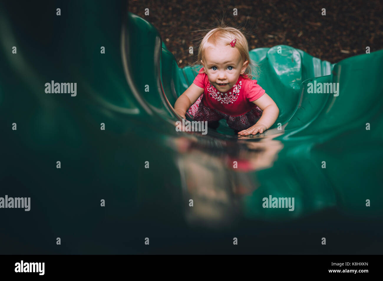 High angle portrait of baby girl playing on slide at playground Stock ...