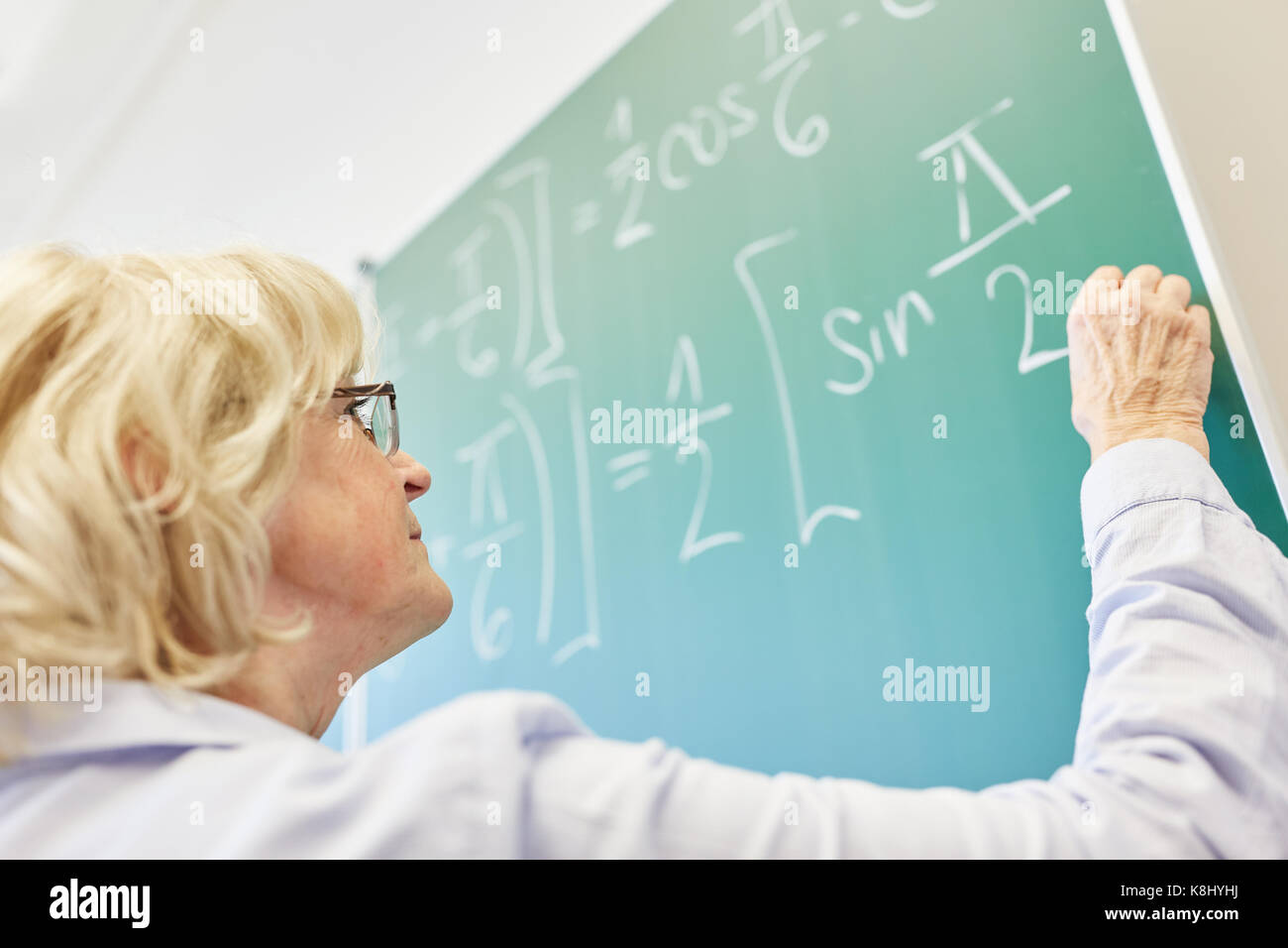 Senior Math lecturer writes on chalkboard in maths seminar Stock Photo