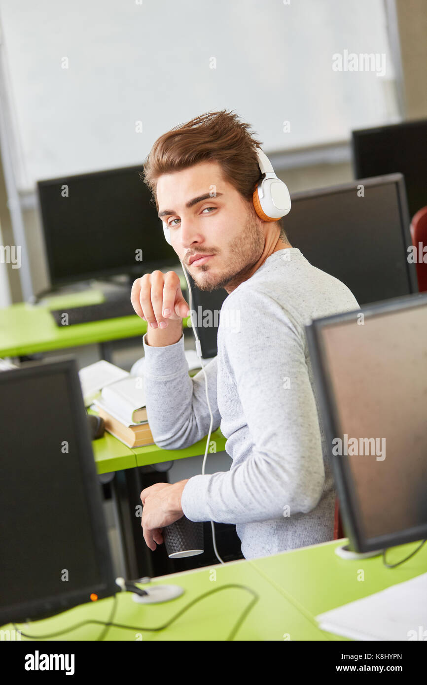 Tired IT student makes an informatics course and wears headphones Stock Photo