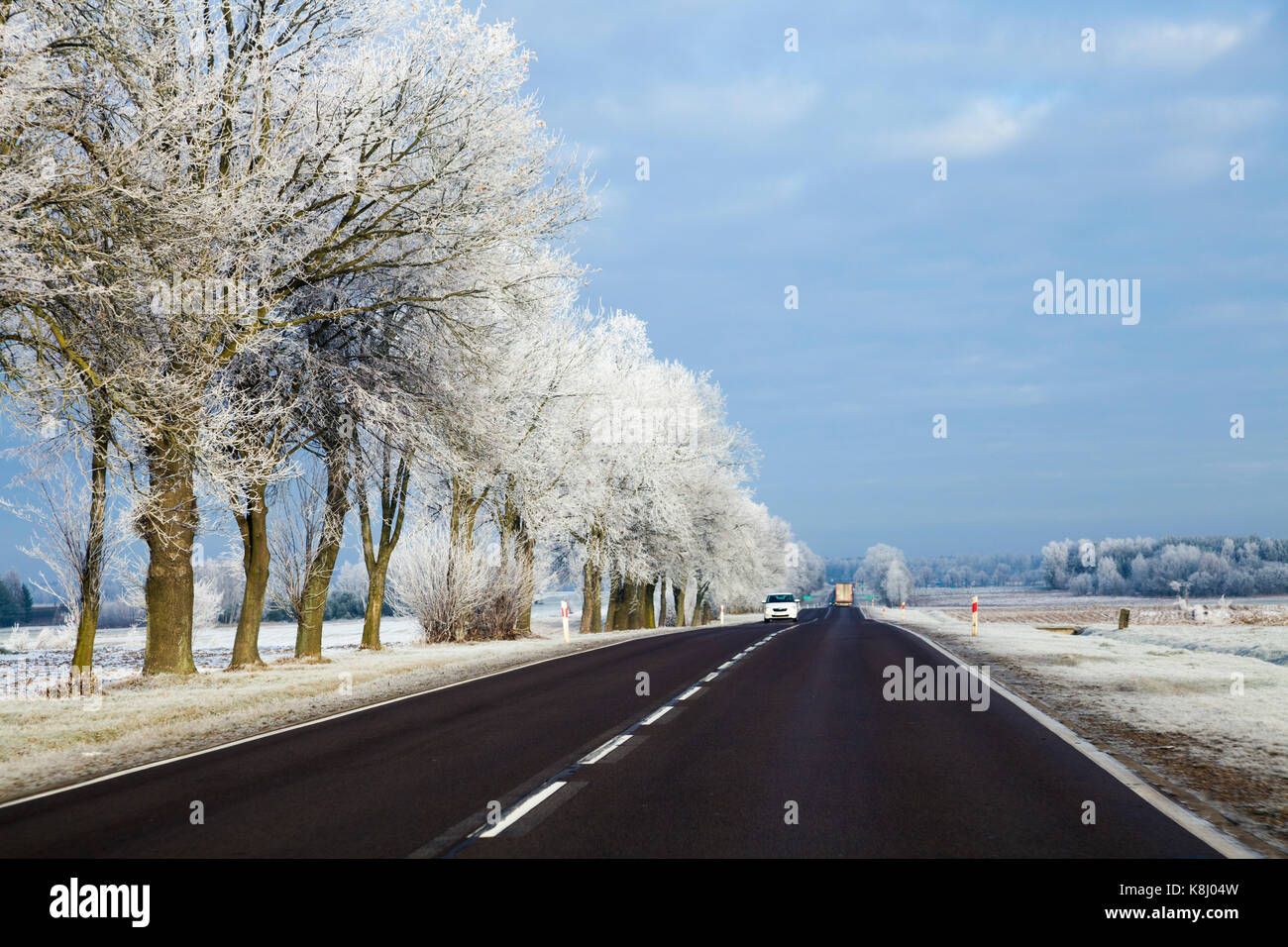 Cars on the road in a wintery landscape with frosted trees Stock Photo