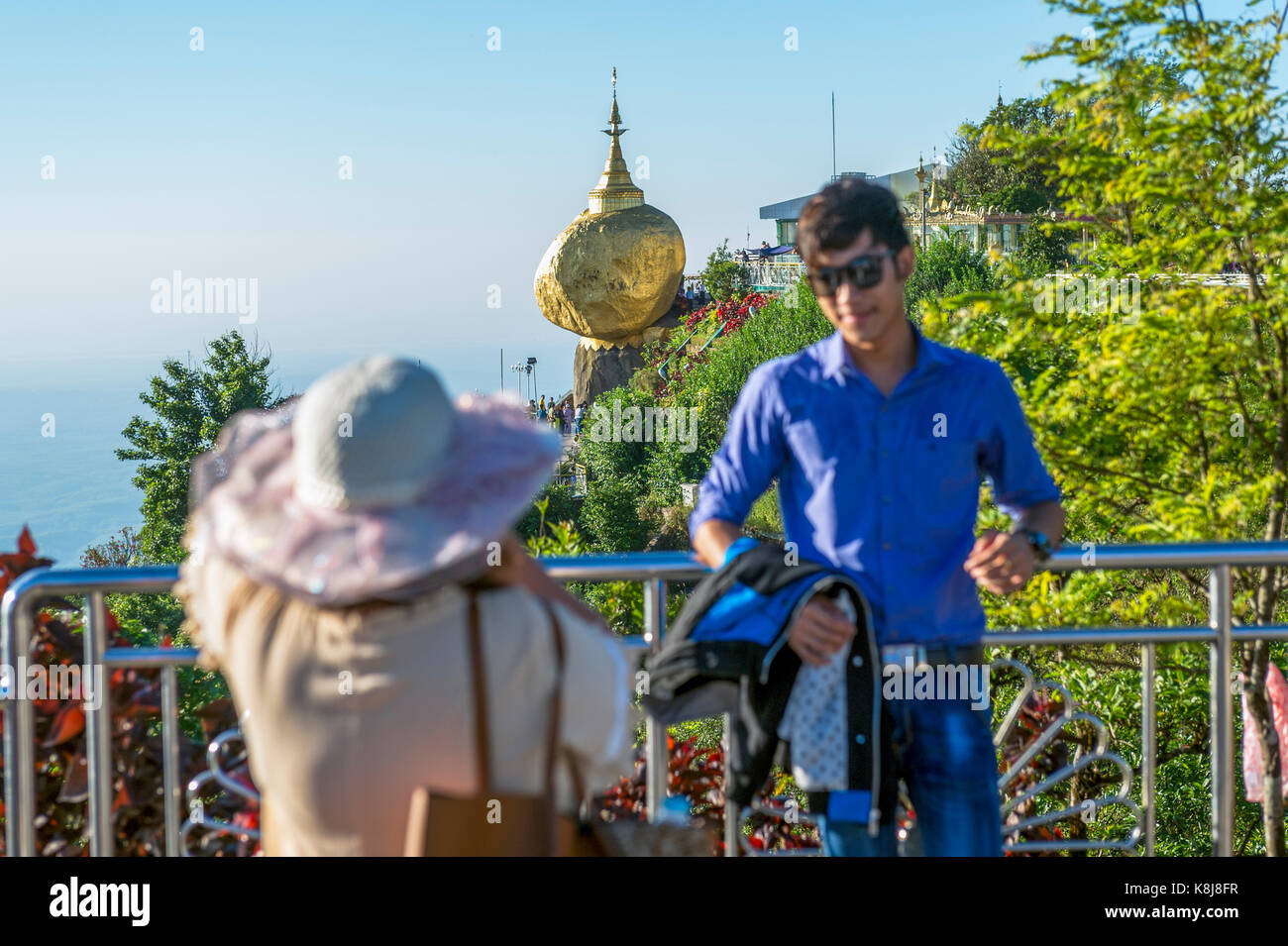 Myanmar (formerly Burma). Kyaiktiyo. State Mon. Sacred site of the golden rock. Tourists photographed in front of the rock Stock Photo