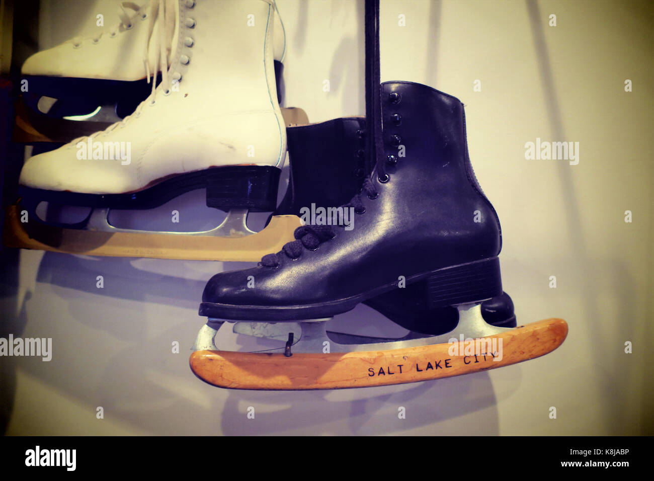 Two pairs of old fashioned ice skates hung on the wall with a black and ...