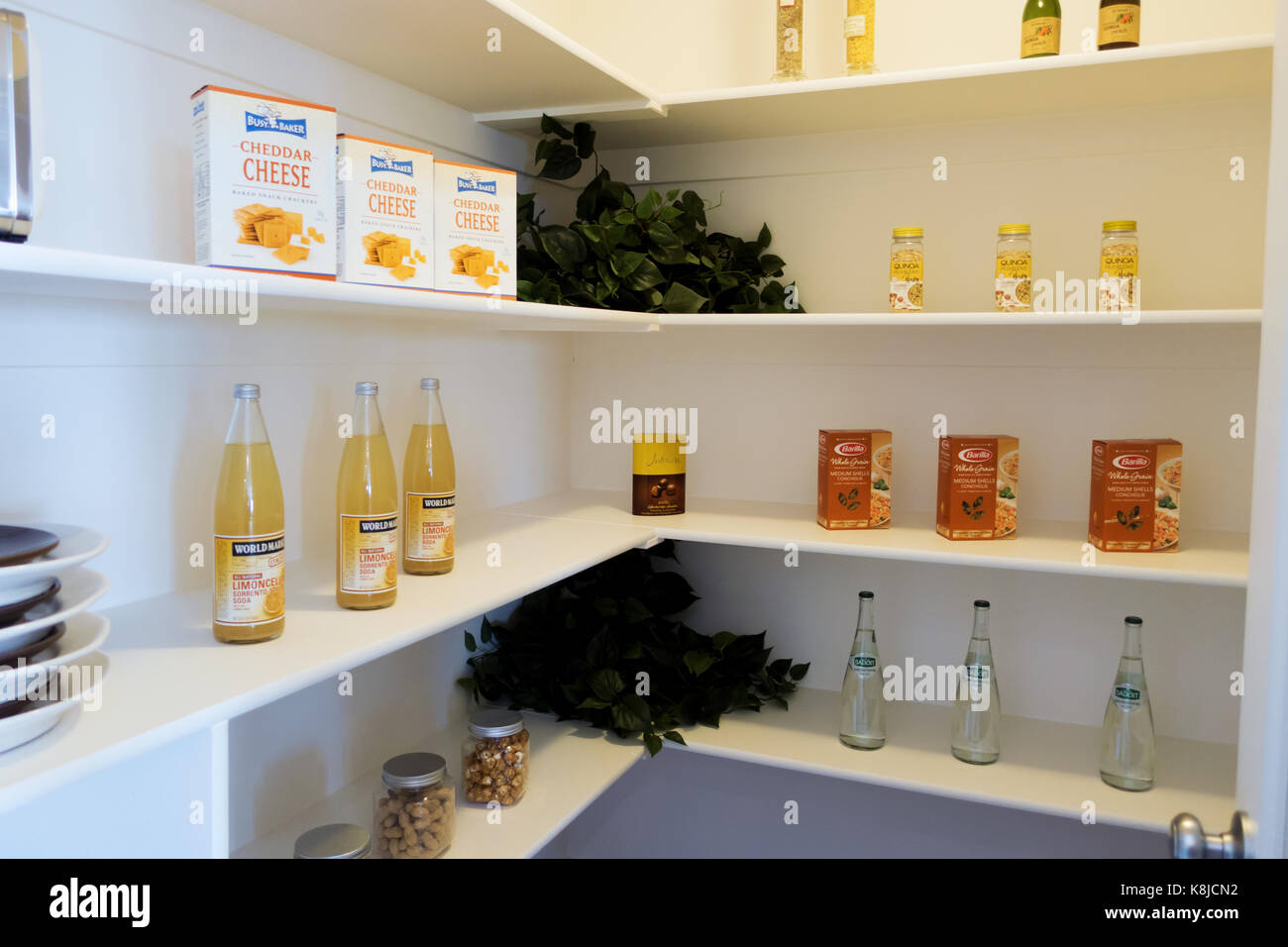 A walk-in kitchen pantry model with jars, wine bottles and boxed food. Stock Photo
