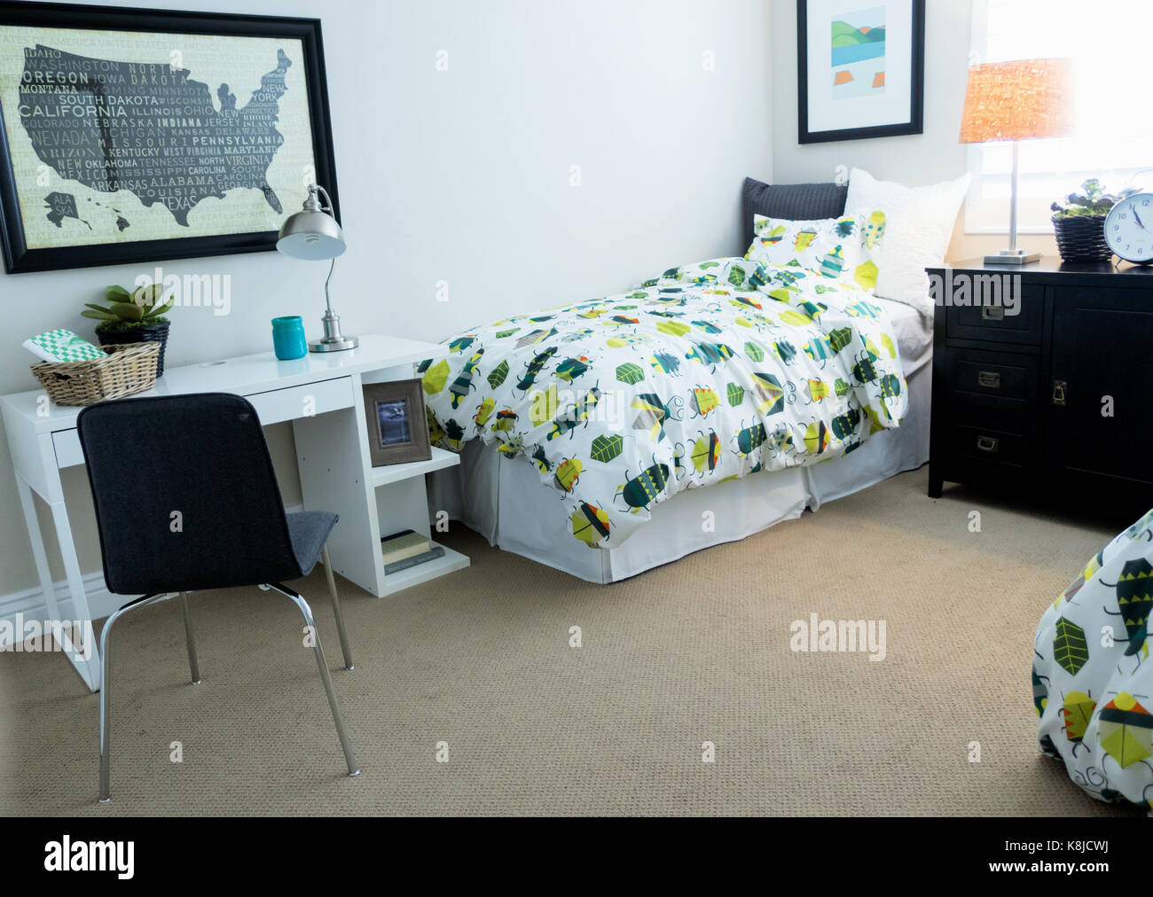 A Bedroom With A Colorful Bug Comforter And A Small Desk Stock