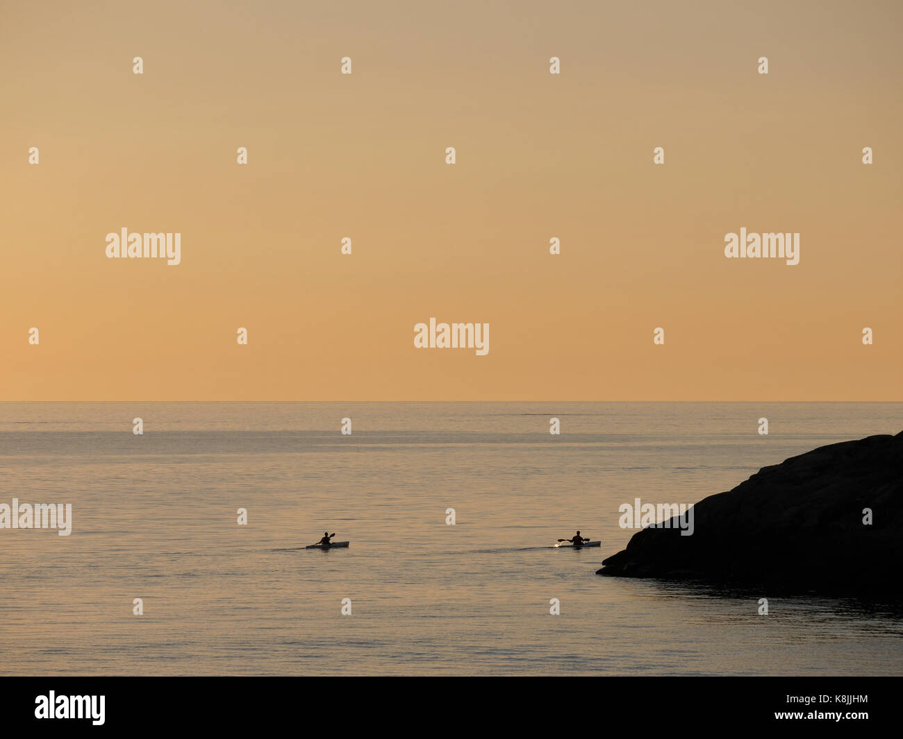 Two persons kayaking in the sunset outside Klåva, Hönö, the archipelago of Gothenburg, Sweden. Stock Photo