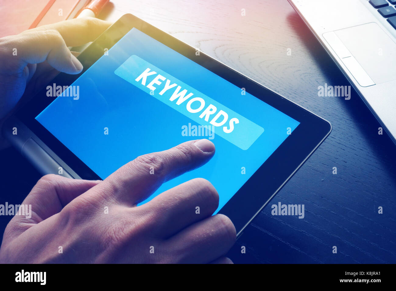 Word Keywords on a tablet as a part of SEO. Stock Photo