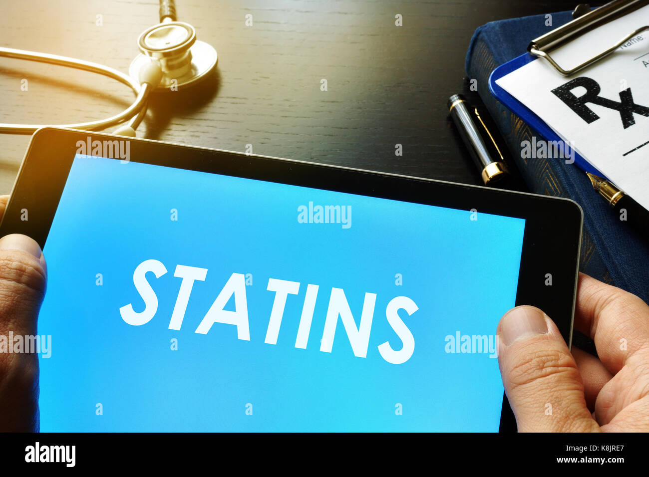 Doctor holding a tablet with word statins. Stock Photo