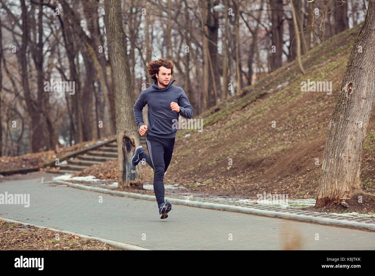 A young male runner runs in the park. Stock Photo