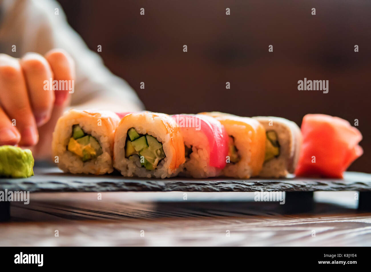 Eating sushi rainbow roll in restaurant Stock Photo