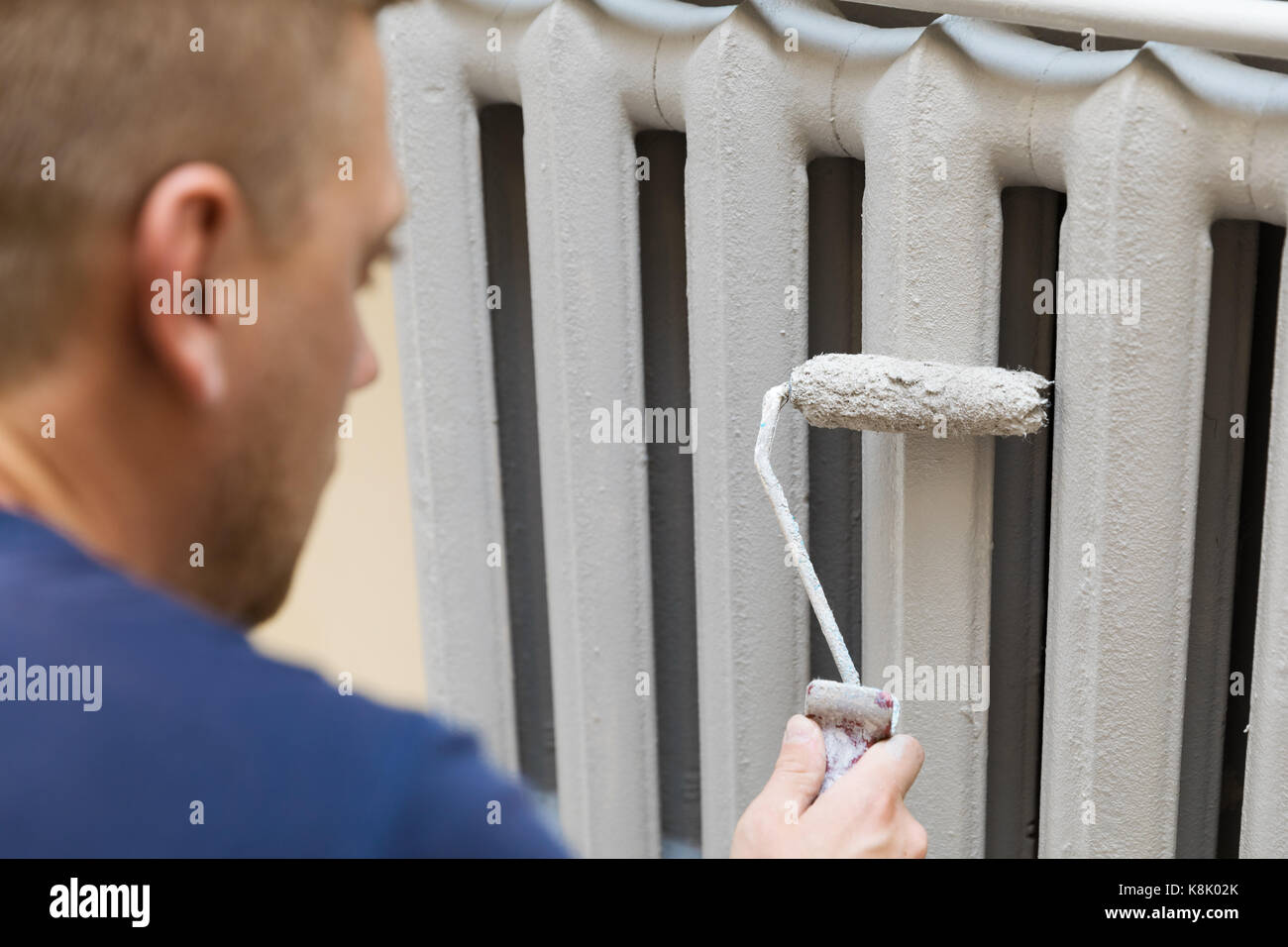 painter paints the cast iron radiator in gray color Stock Photo Alamy