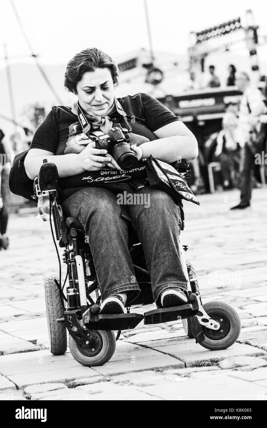 Handicapped woman sitting on wheelchair watching her camera Stock Photo
