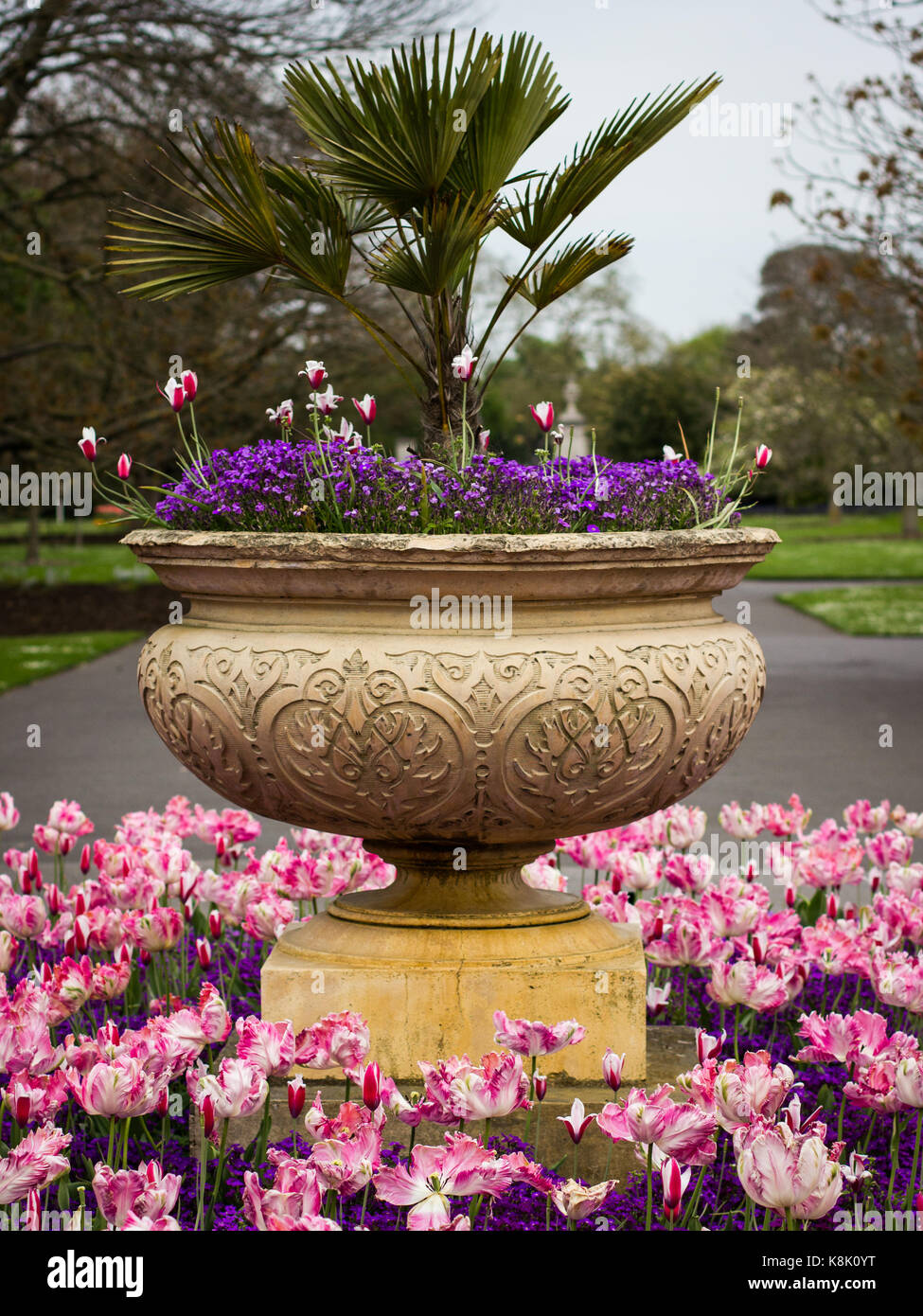 A beautiful stone urn houses a myriad of bright flowers Stock Photo