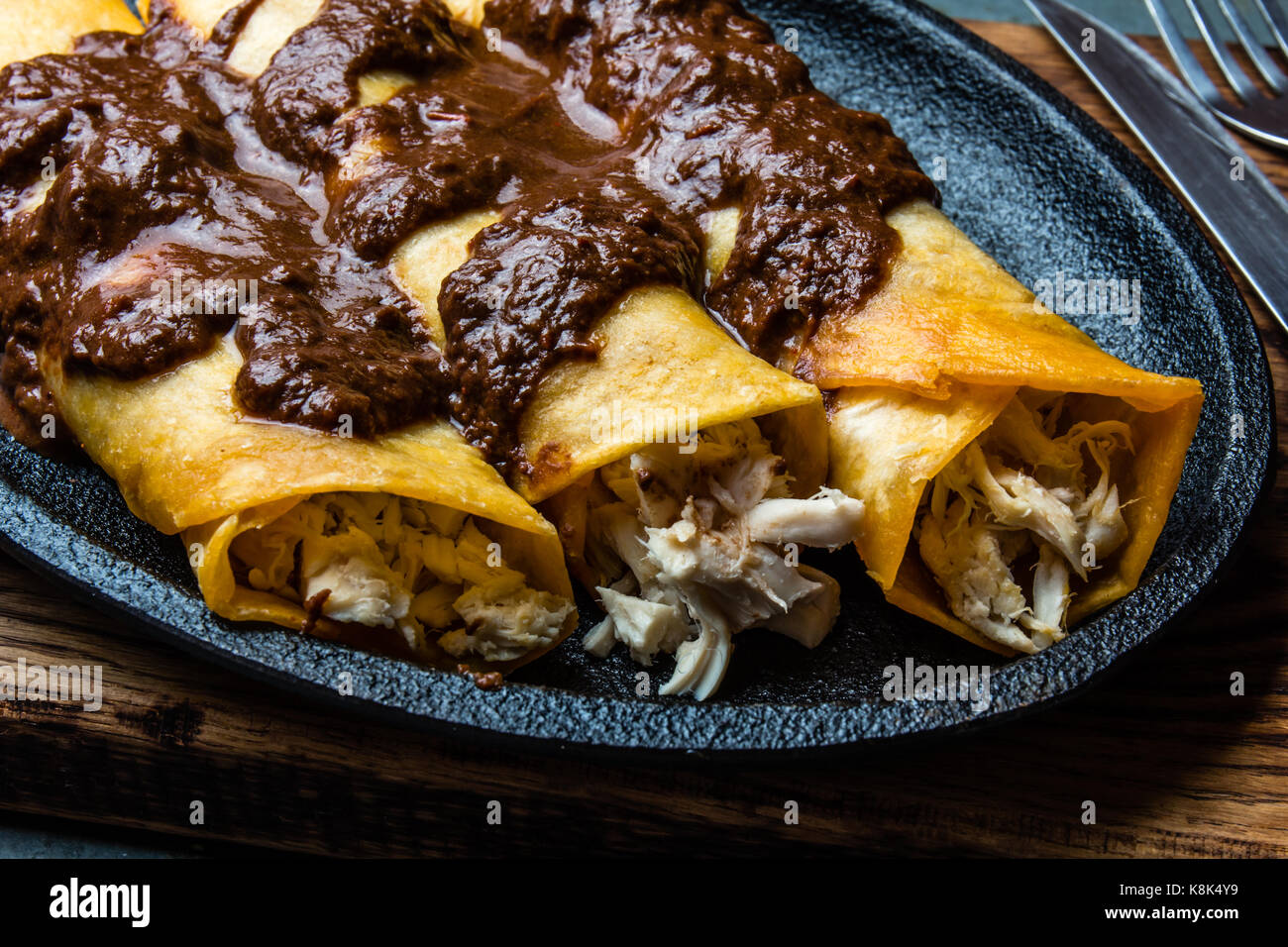 Mexican cuisine. Traditional Mexican chicken enchiladas with spicy chocolate salsa mole poblano. Enchiladas with sauce moole from Puebla, Mexico. Stock Photo