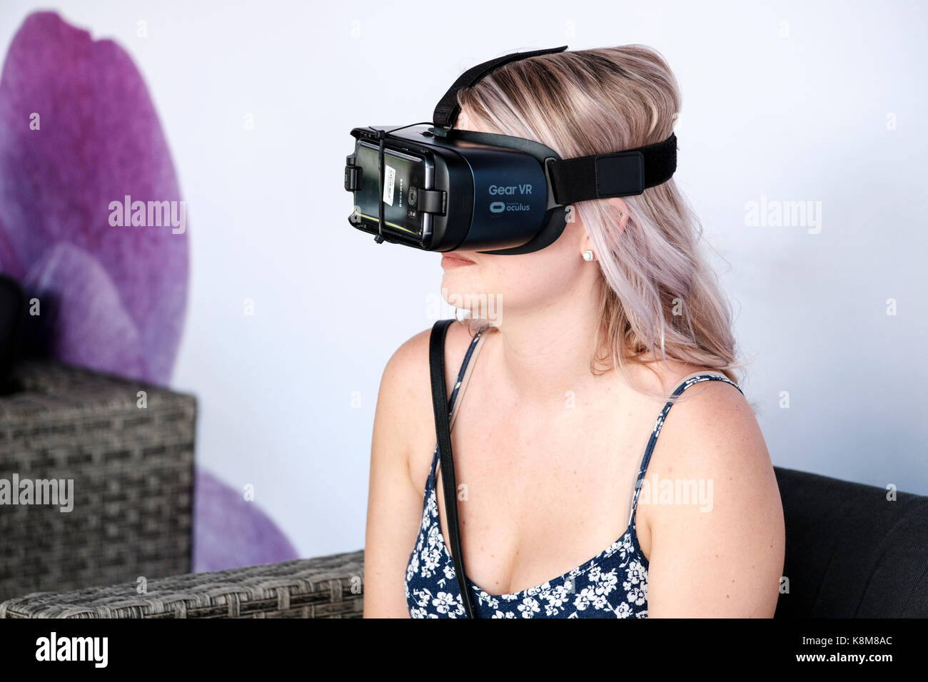 Teenager girl wearing Oculus Gear VR headset, virtual reality (VR) equipment with Samsung phone. Stock Photo