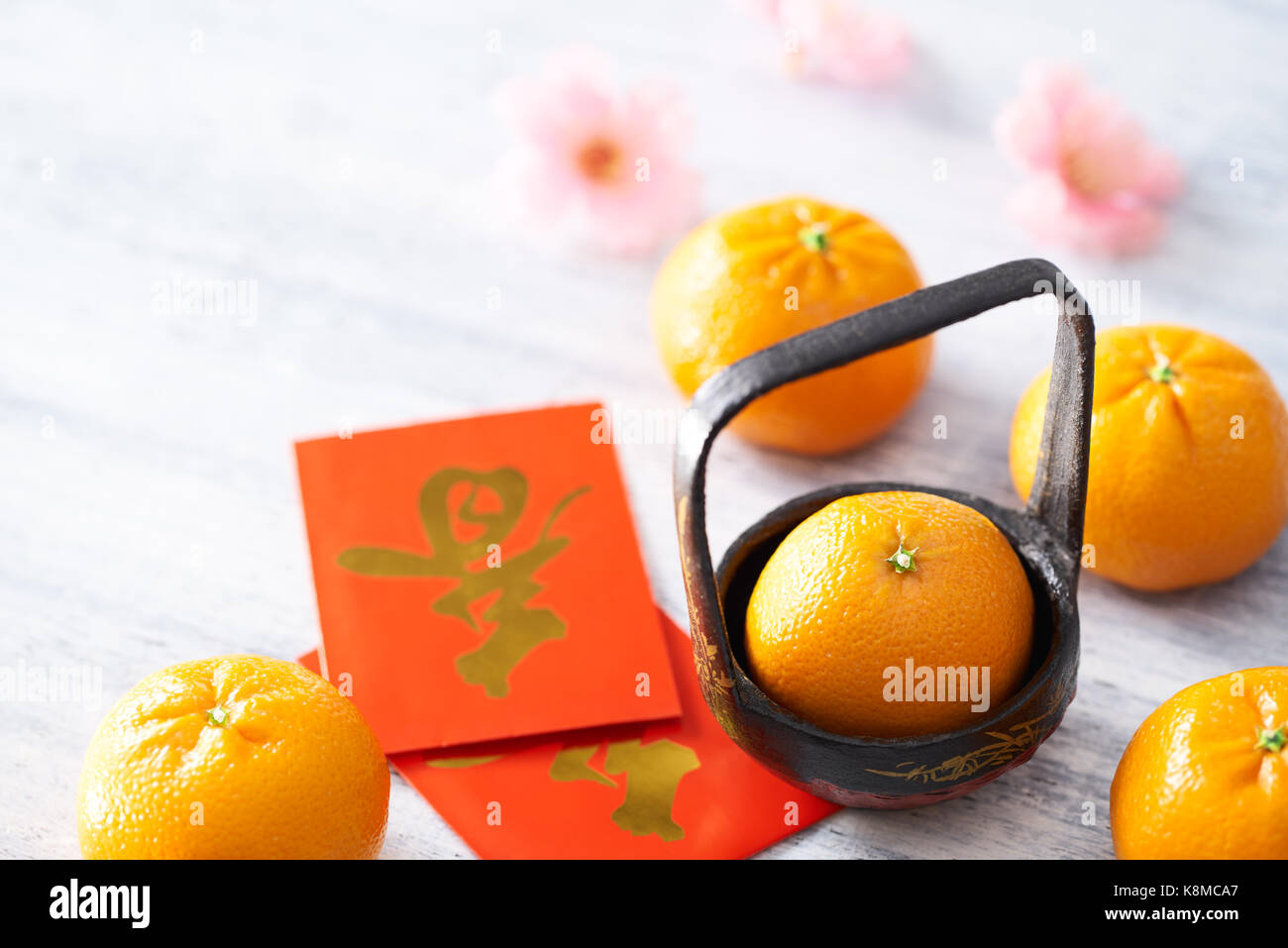 Chinese New Year - Mandarin orange and red packet (Foreign text means spring season) on white painted wood table Stock Photo