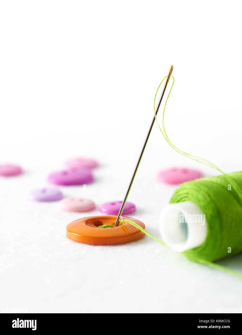 Sewing needle and thread with buttons over white background Stock Photo