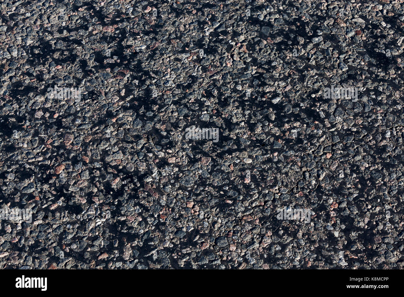 The texture of an asphalt road made of small stones and covered with black  resin. Photo of a close-up of a small section of the route Stock Photo -  Alamy