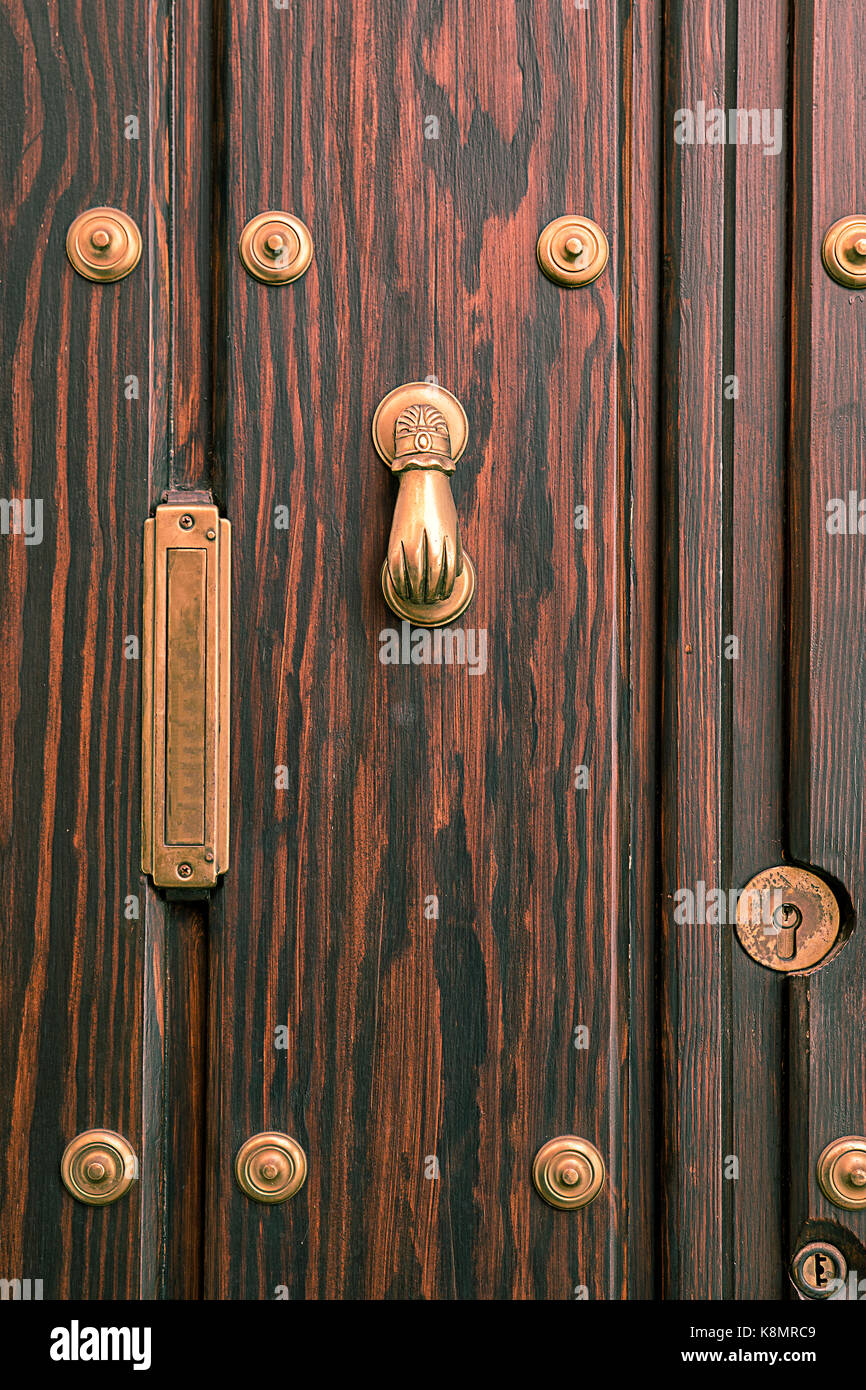 typical  door knocker  on wooden door with golden  knocker and rivet and mailbox for letters Stock Photo