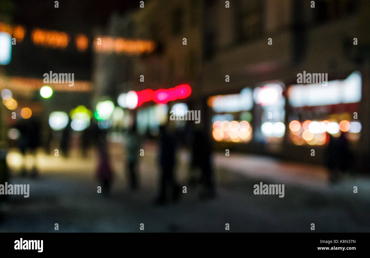 A crowd of people moving on the old european city night street defocused blurred abstract image Stock Photo