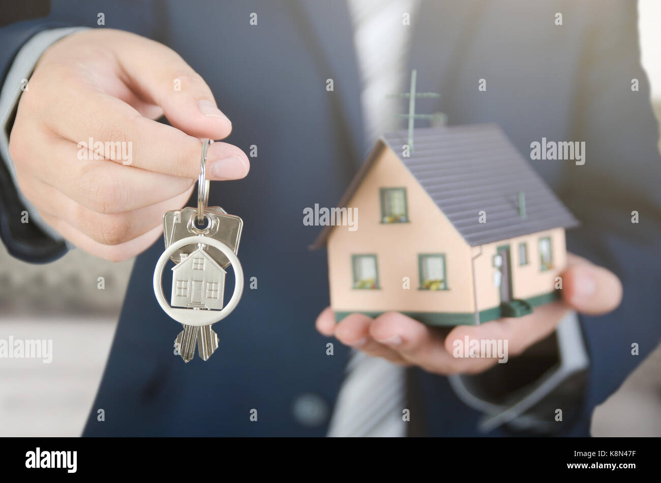 Real estate agent with home keys and house miniature. realestate key