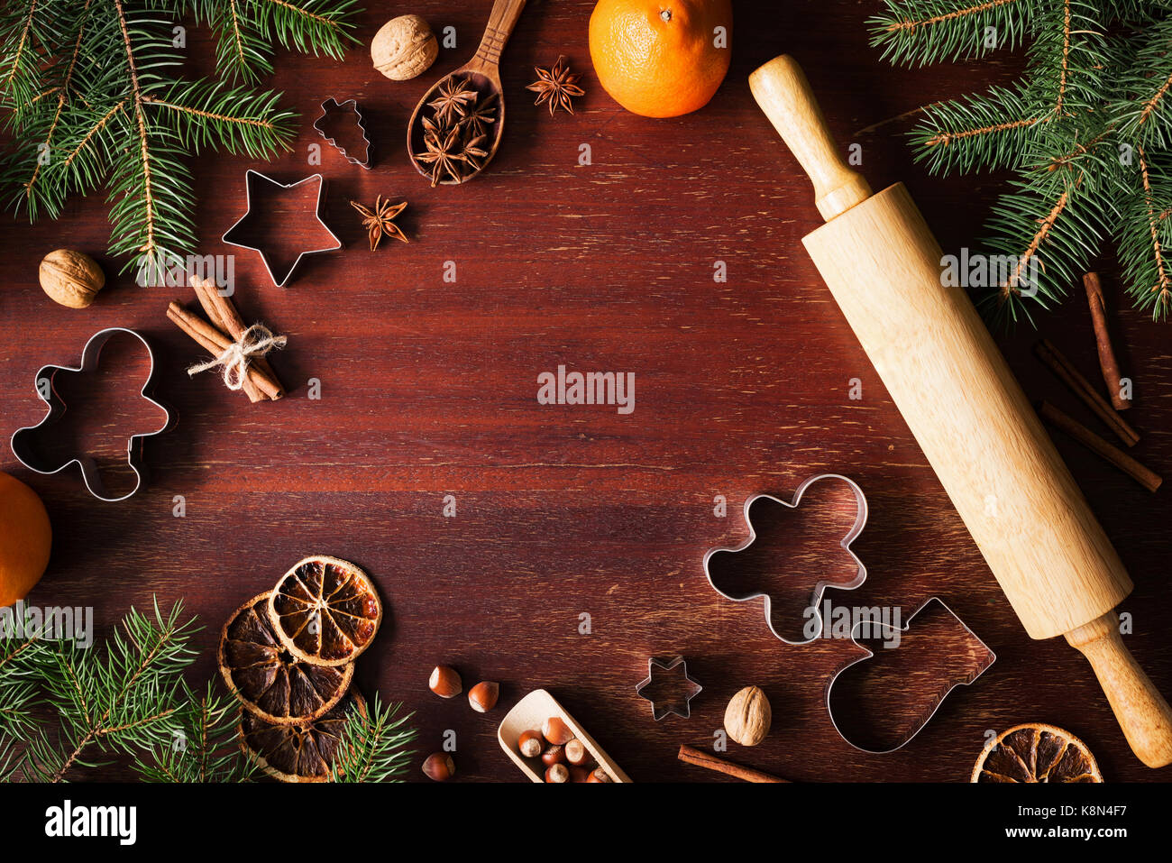 Winter holidays Christmas New Year background with cookie cutters, spices, nuts, Christmas tree and Gingerbread cookies on wooden background. Top view Stock Photo